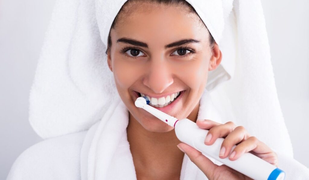 Beautiful Woman In Bathrobe Brushing Teeth