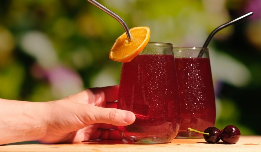 Female hand with summer cherry cocktails 