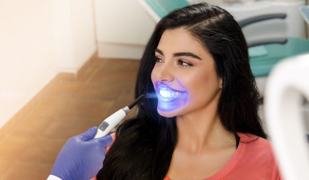 Gorgeous young woman UV lamp teeth whitening