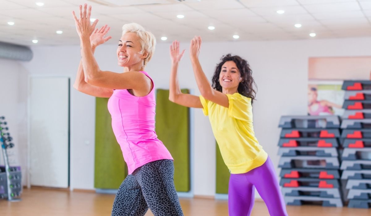 Happy female athletes doing aerobics exercises or Zumba dance workout
