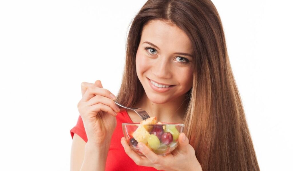 Pretty young woman eating fruits