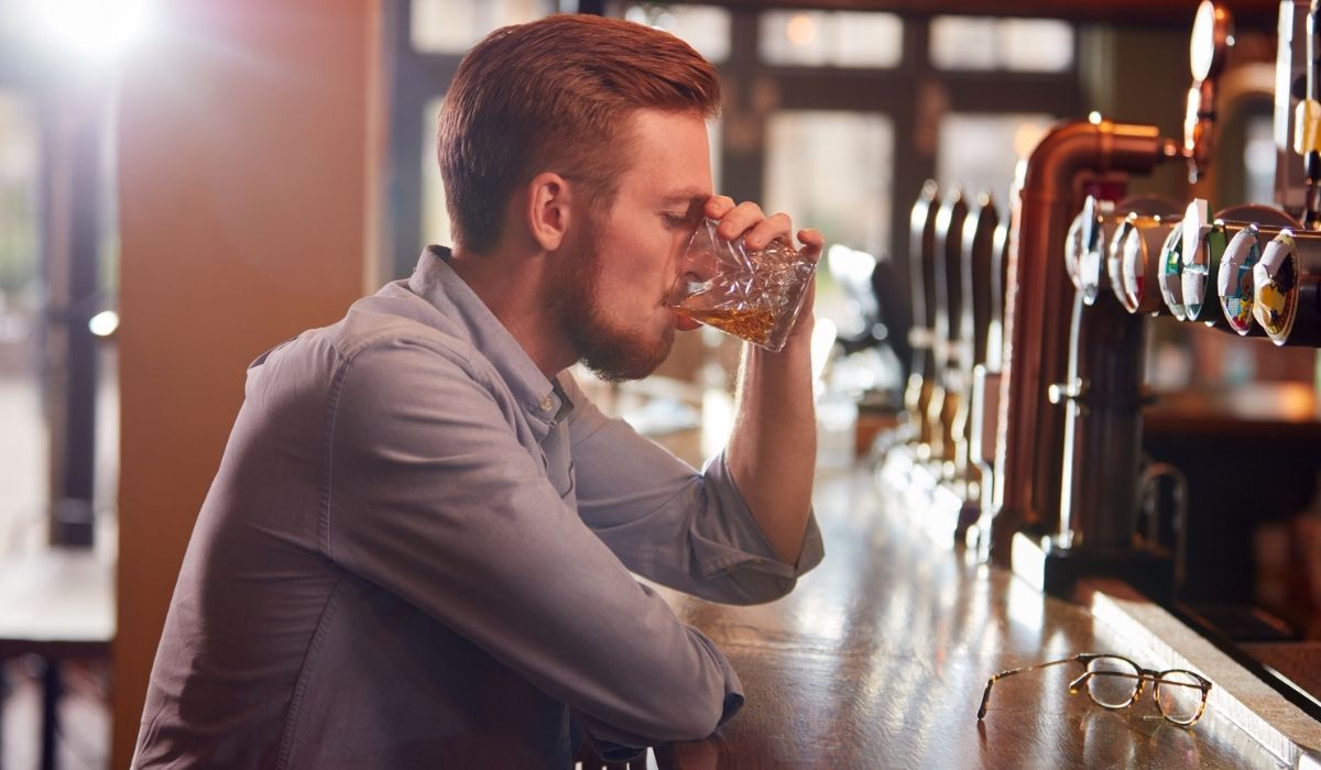 Unhappy Man Sitting At Pub Bar Drinking Alone