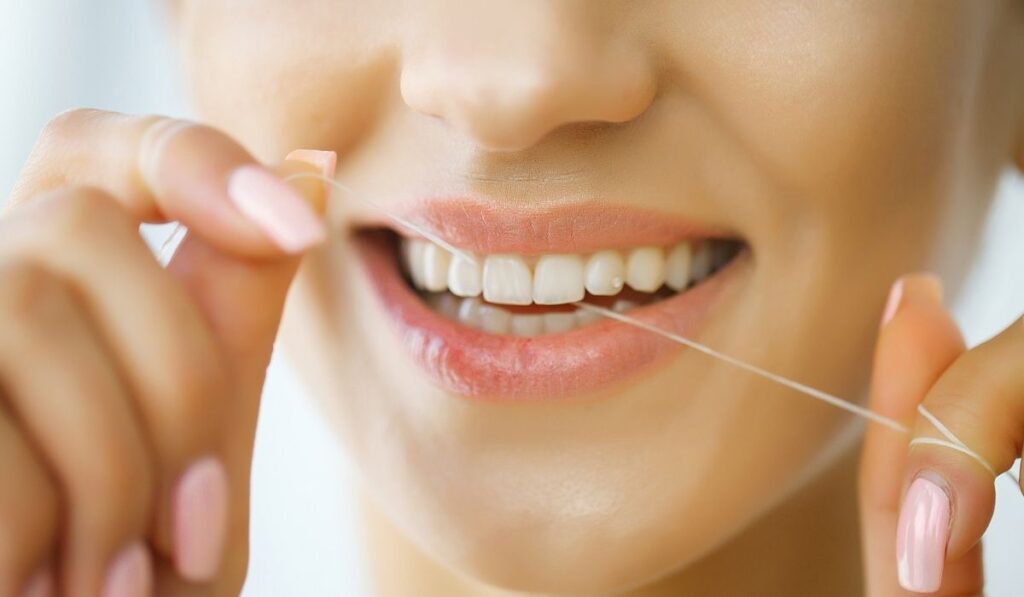 Woman With Beautiful Smile Using Floss For Teeth 
