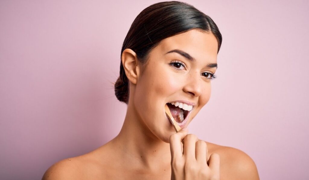 Young beautiful brunette woman brushing her teeth using tooth brush 