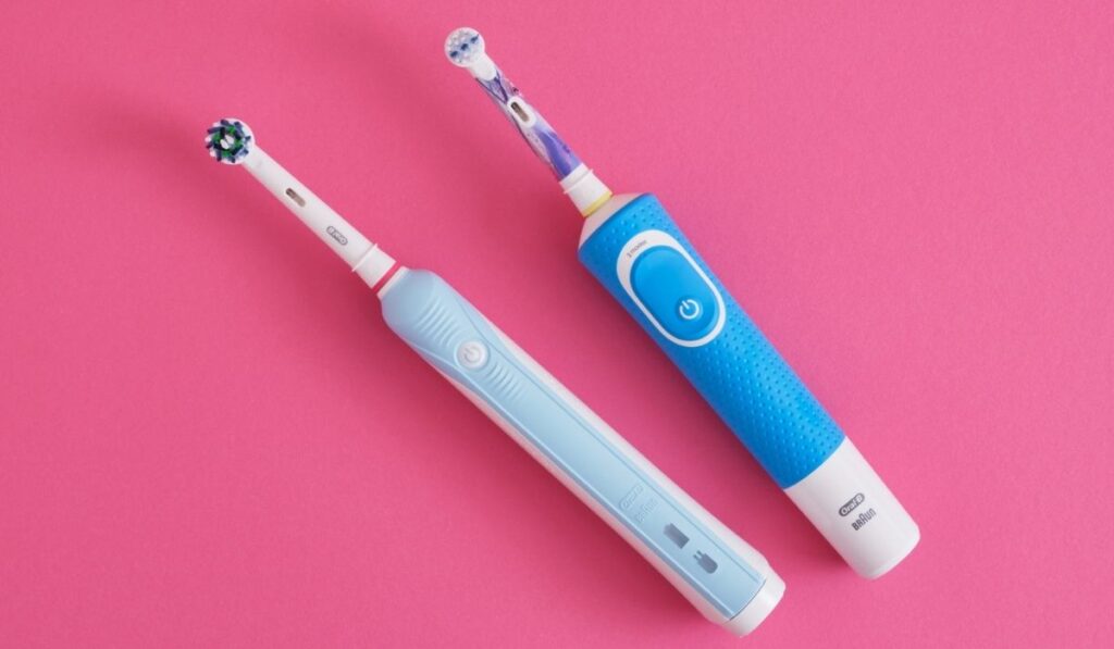 two electric blue toothbrushes on bright pink background
