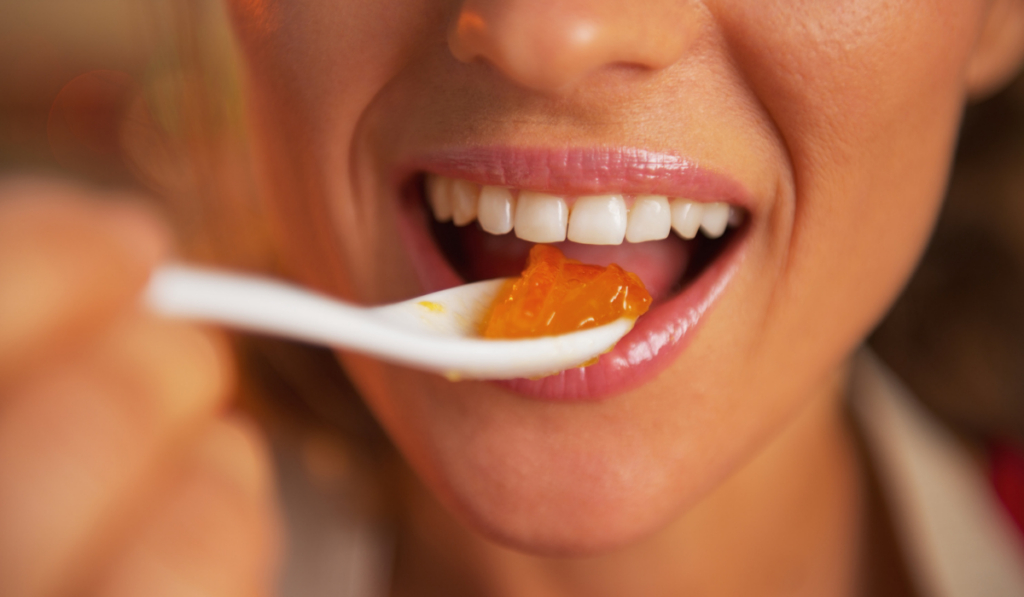 Closeup on happy woman eating orange jam