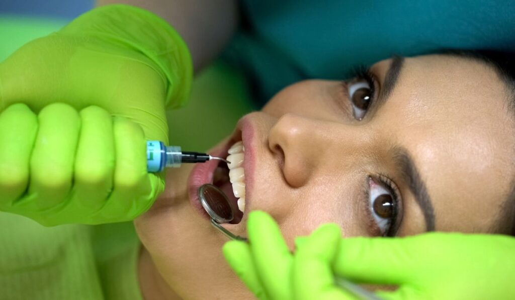 Dentist putting blue gel on tooth, modeling paste
