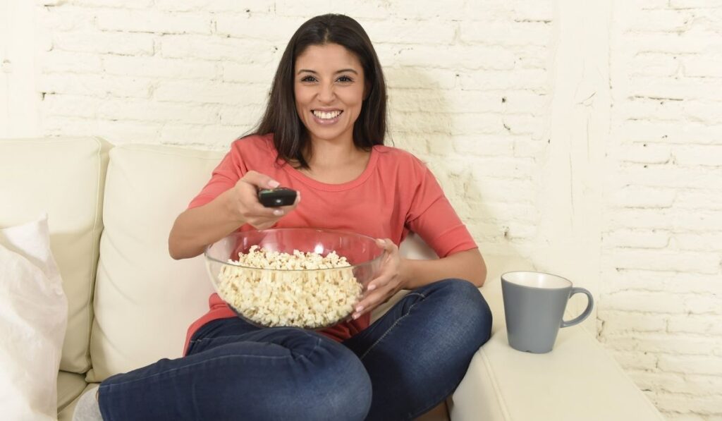 Happy woman eating popcorn watching television 