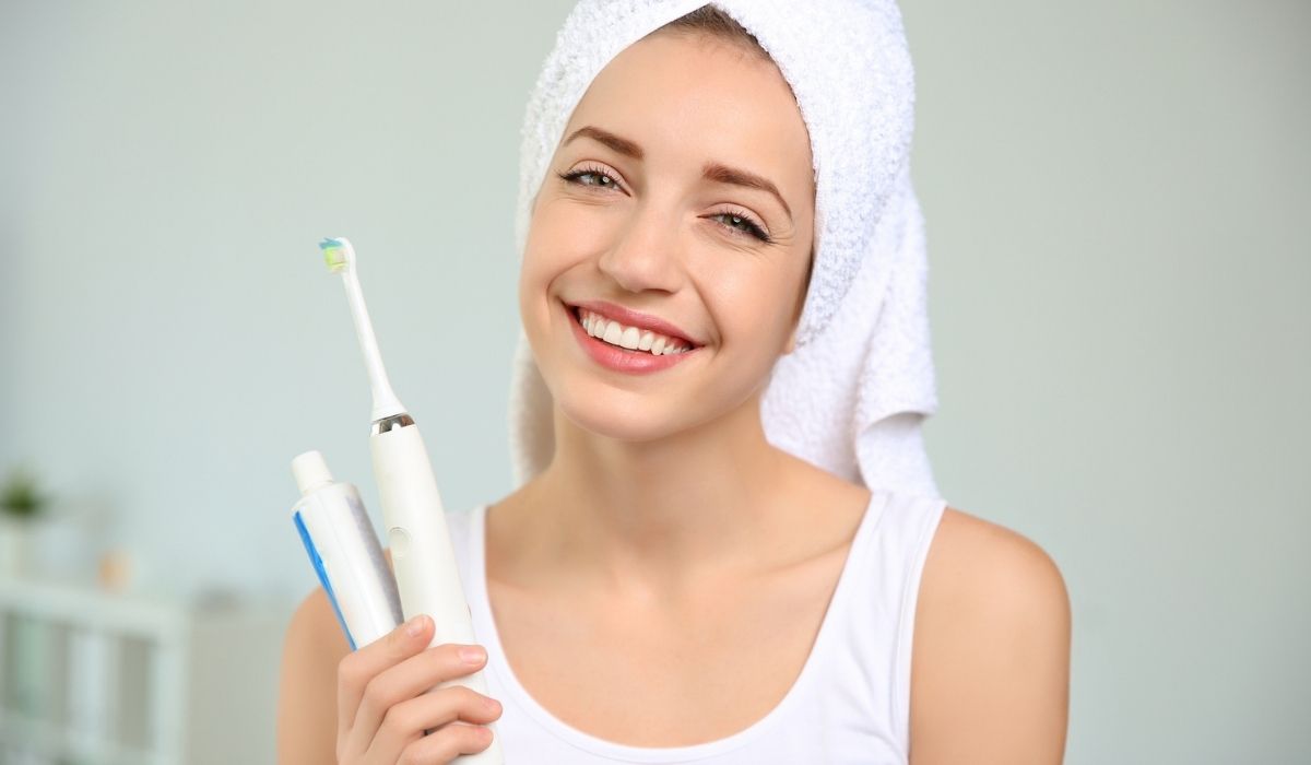 Portrait of young woman with electric toothbrush and paste