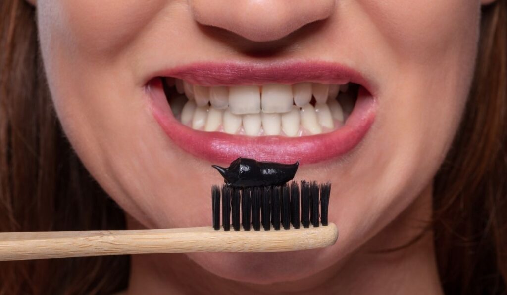 Woman Holding Tooth Brush With Black Active Charcoal Toothpaste