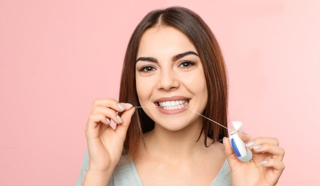 Young woman flossing teeth