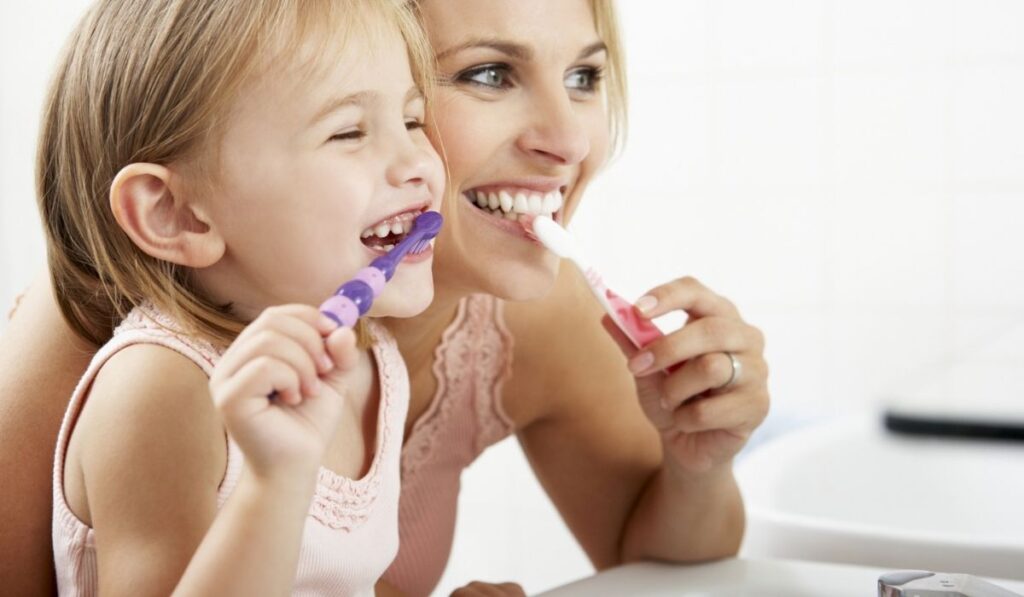 Mother And Daughter Brushing Teeth Together 