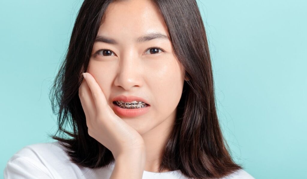 Young asian woman wearing braces toothache unhappy lack of confidence
