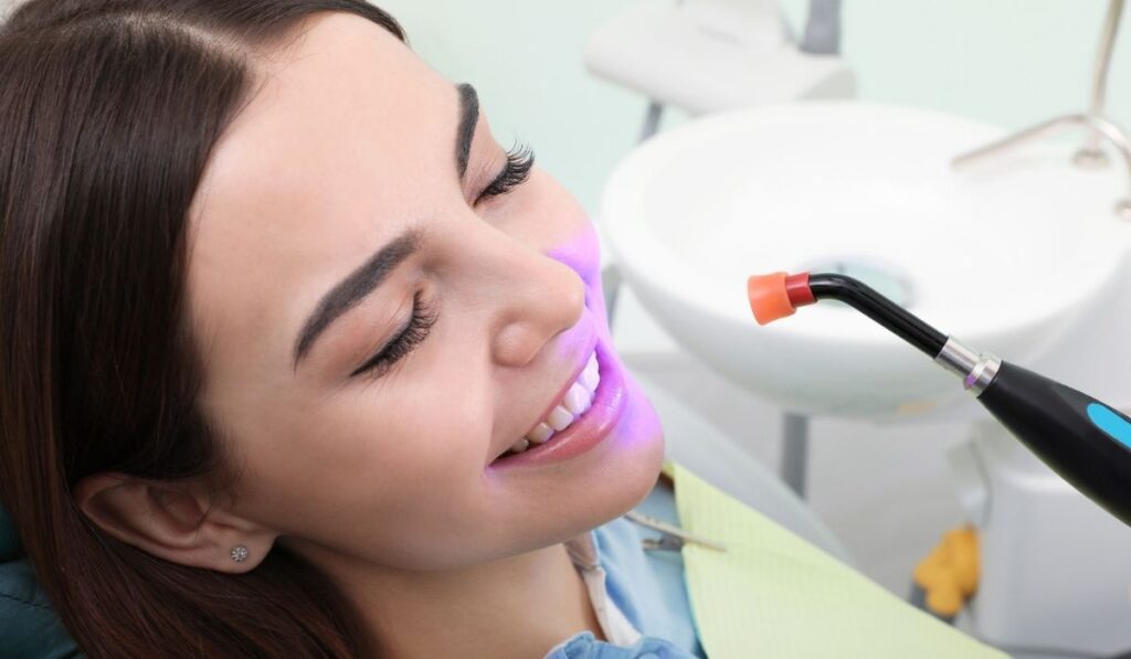 Woman undergoing teeth whitening procedure in clinic 