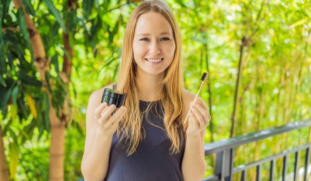 Young woman brush teeth using Activated charcoal powder for brushing and whitening teeth