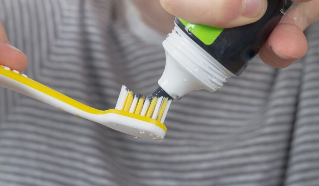 Brushes his teeth with a black charcoal toothpaste