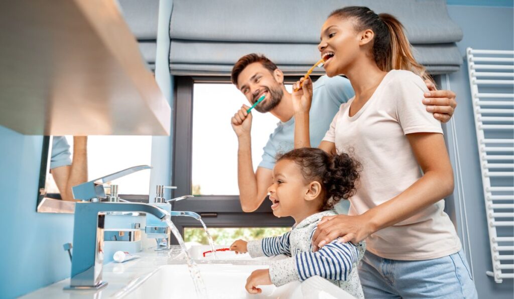 Mother, father and daughter brushing teeth in bathroom