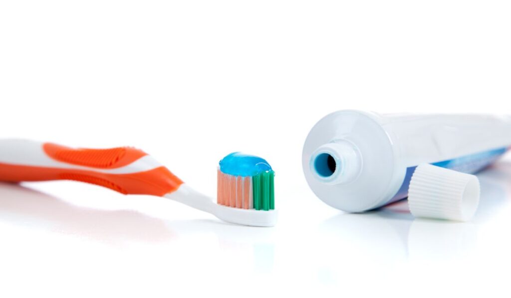 Orange toothbrush with toothpaste on white
