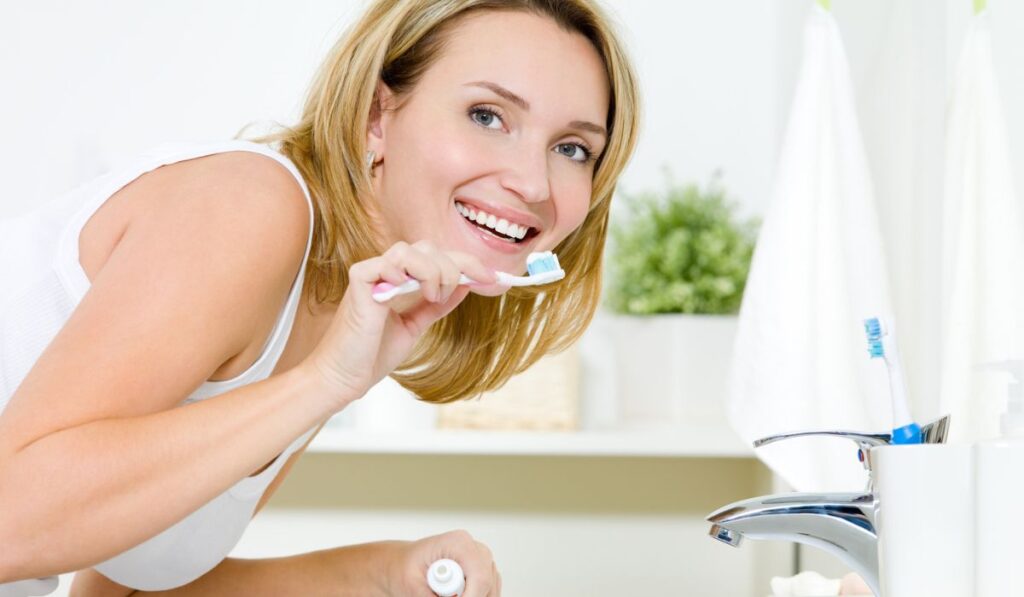Smiling woman cleaning teet
