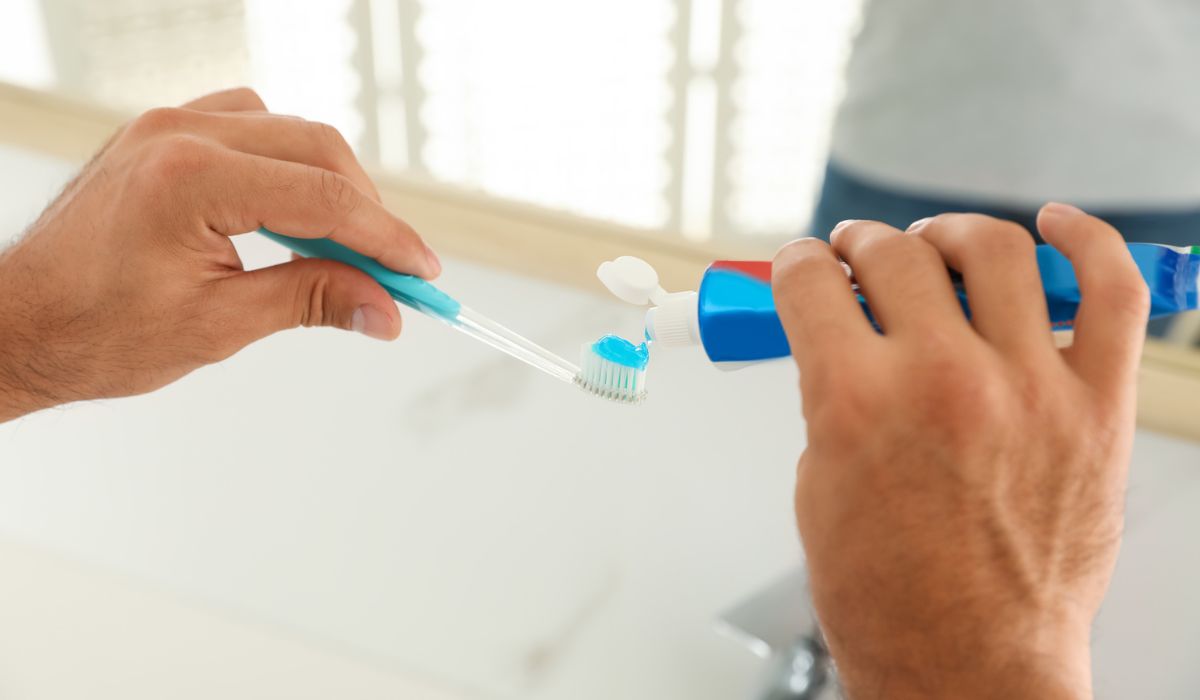 Man applying toothpaste on brush in bathroom