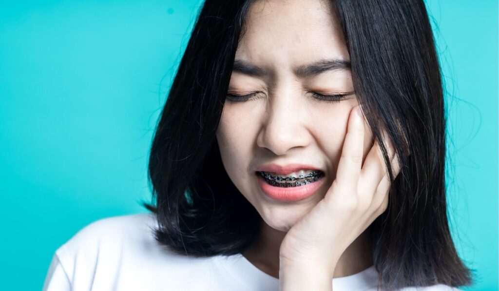 Teenage woman wearing braces and she is having a toothache