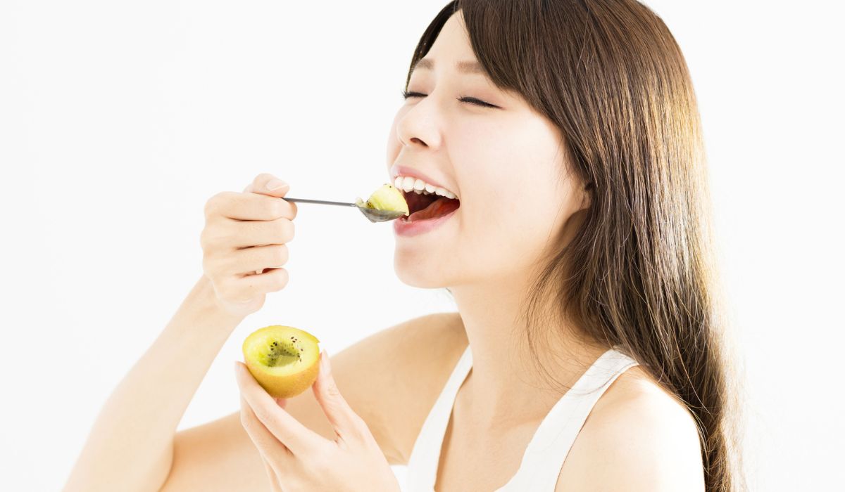 young woman eating kiwi fruit