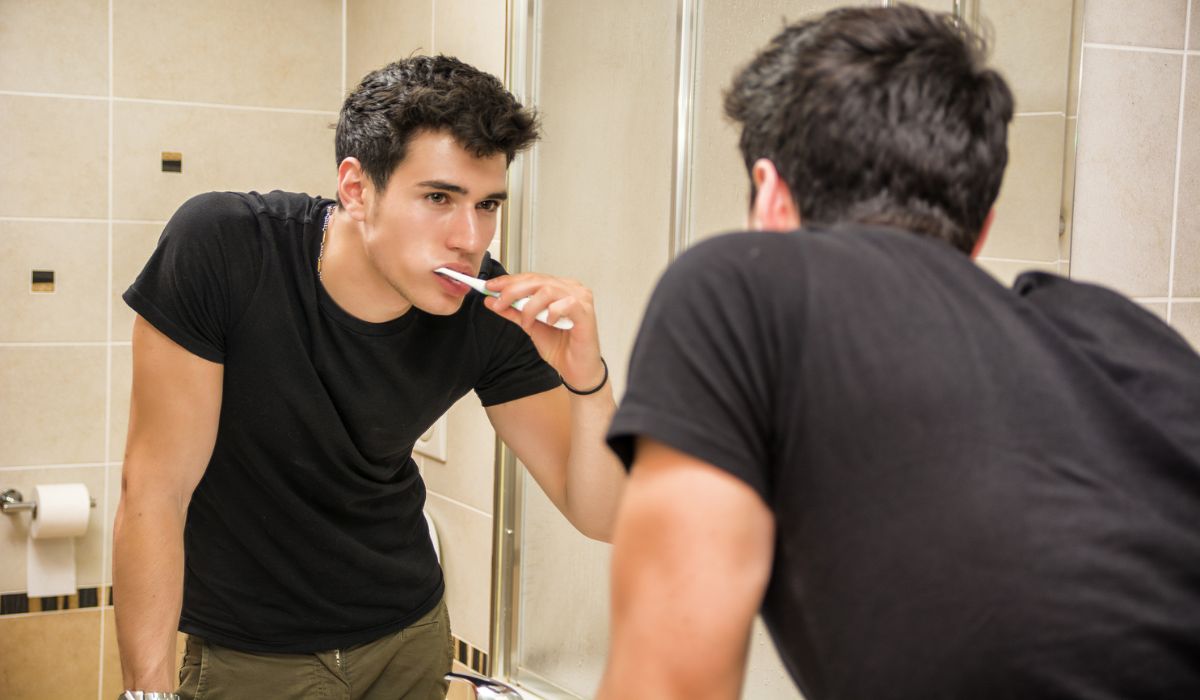 Headshot of attractive young man brushing teeth