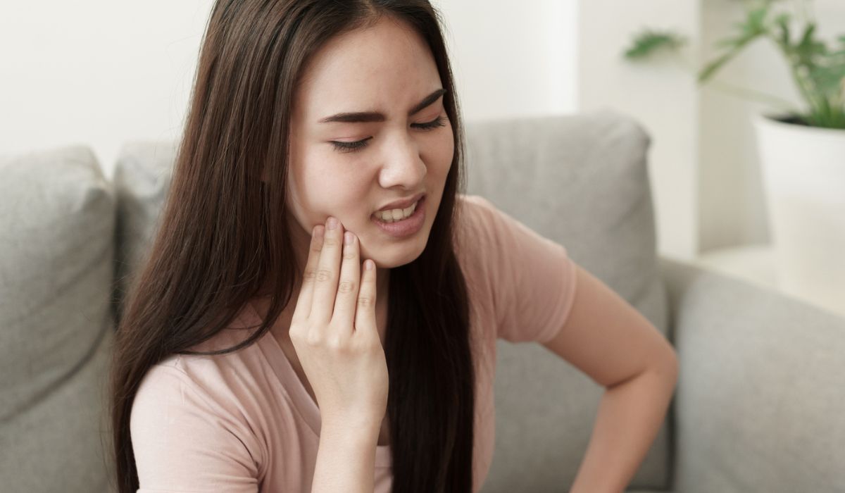 Asian women have toothache pain while sitting on the sofa at home