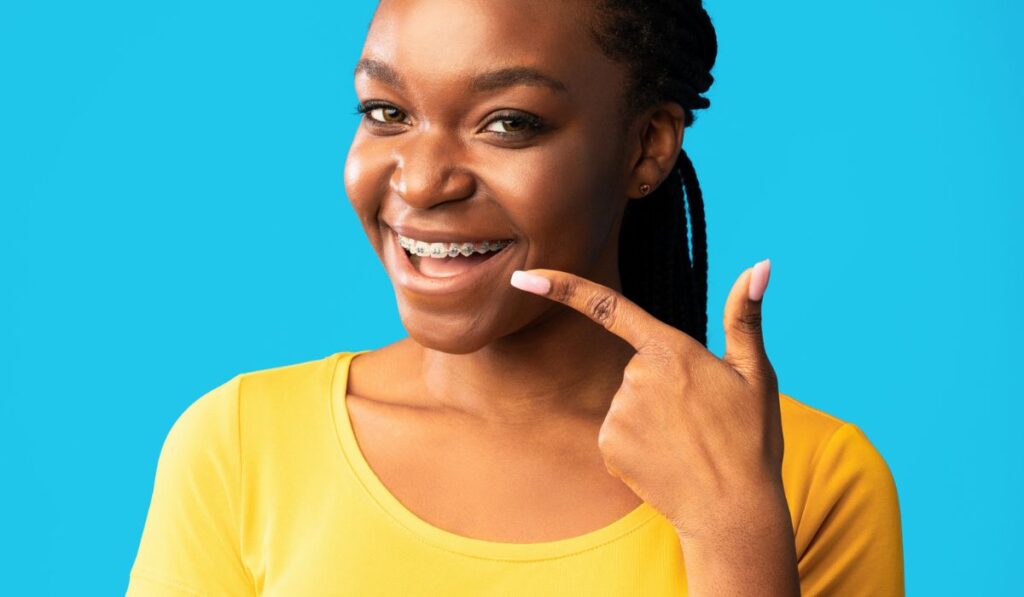 African Lady In Braces Pointing Finger At Teeth