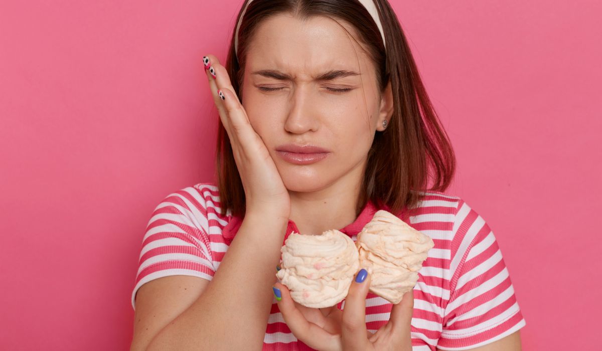 indoor shot of sad unhealthy woman wearing striped t shirt posing isolated over pink background