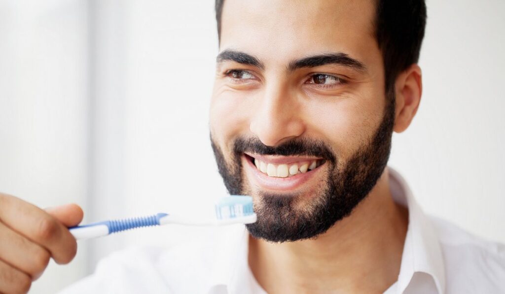 Beautiful Smiling Man Brushing Healthy White Teeth With Brush