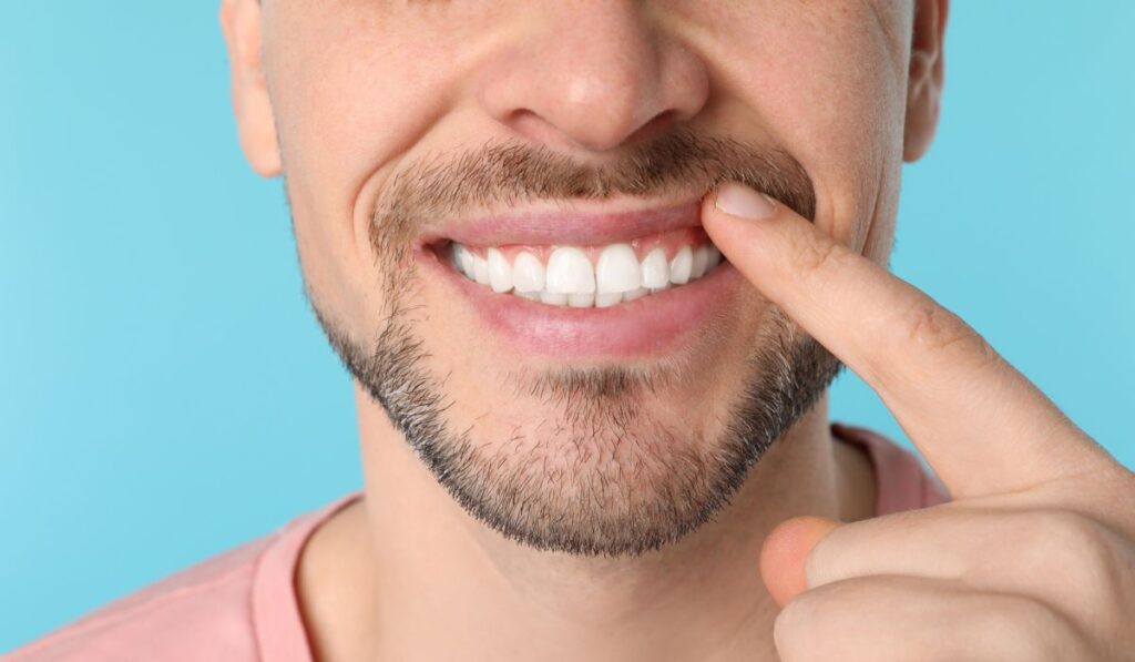 Smiling man showing perfect teeth on color background