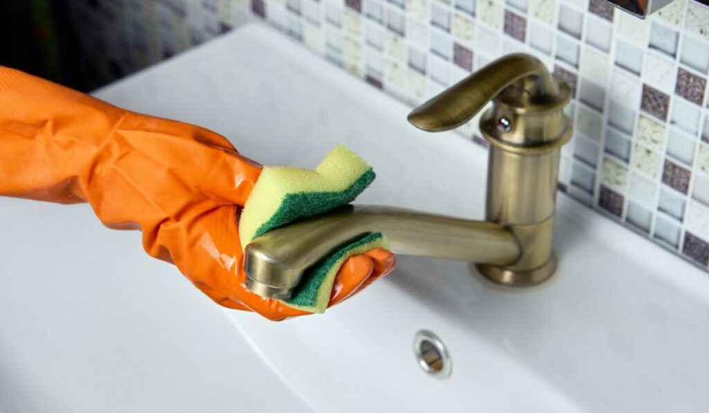 Using latex gloves when wiping brass faucet with cleaning sponge