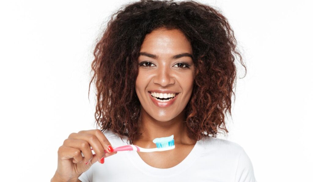 African lady holding toothbrush with toothpaste