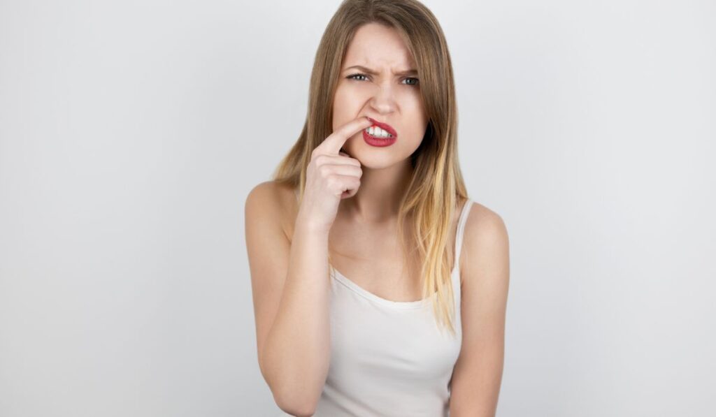 Young beatuiful blond woman standing on isolated white background suffering from sudden gum pain