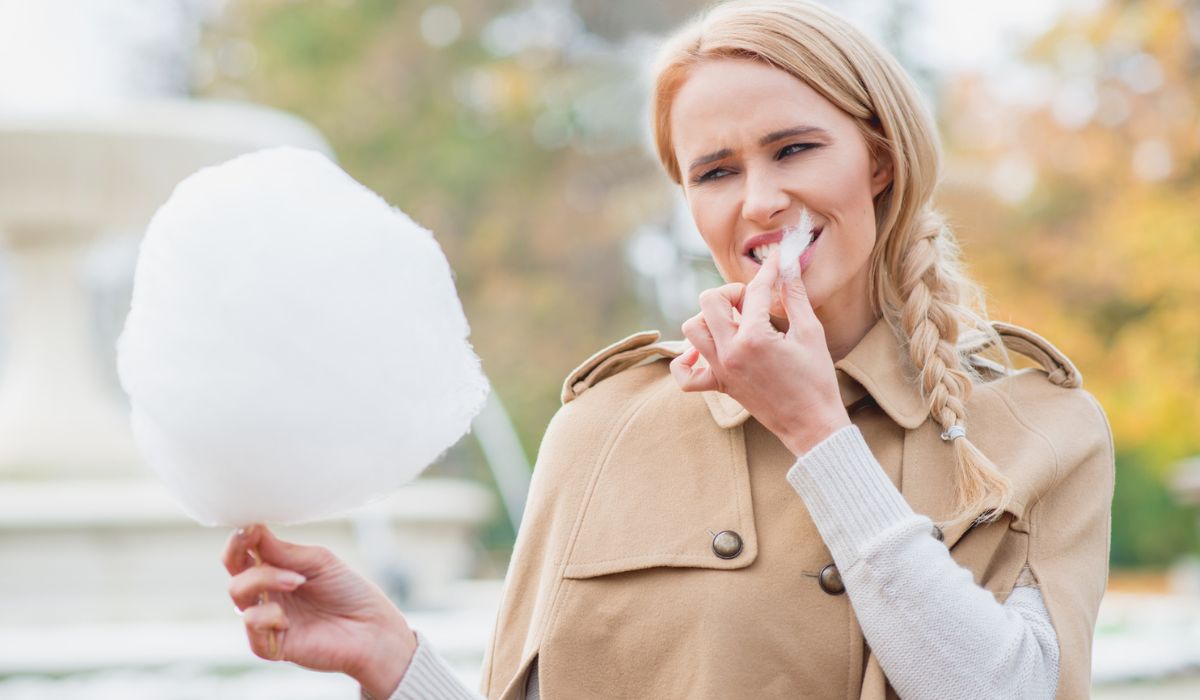 Pretty blond woman eating candy floss